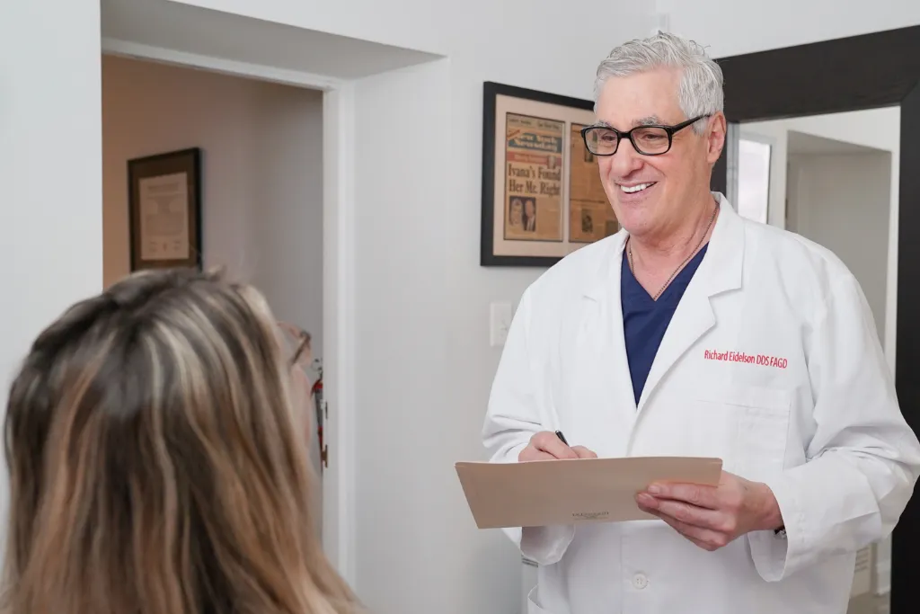 Dr. Eidelson Holds Clipboard While Taking Notes During Discussion With Patient